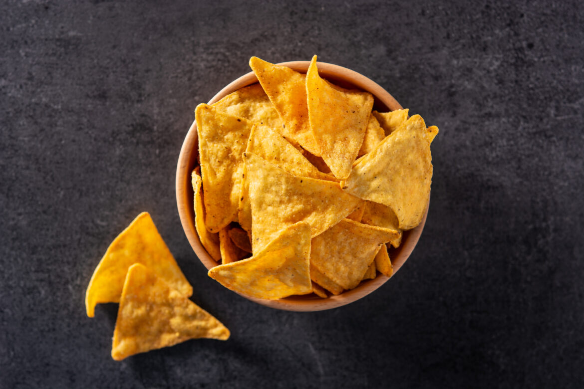 Nachos in wooden bowl on black slate background. Top view Chips in einer Schüssel